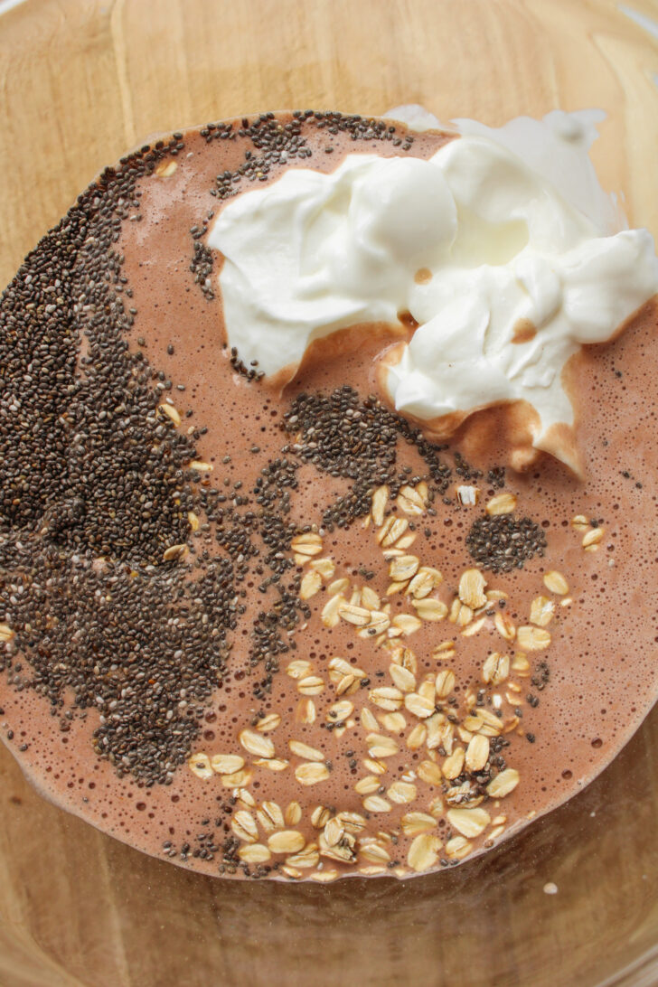 chocolate milk, oats, chia seeds and greek yogurt in a glass bowl