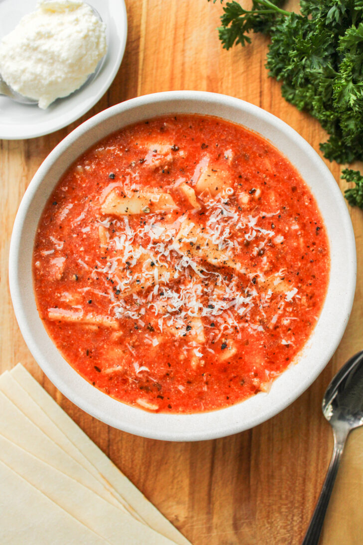 one pot lasagna soup in a white ceramic bowl on a wooden board