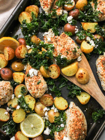 Mediterranean Sheet Pan Chicken Thighs and Potatoes with a wooden spatula picking up food