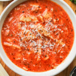 close up of one pot lasagna soup in a white ceramic bowl on a wooden board