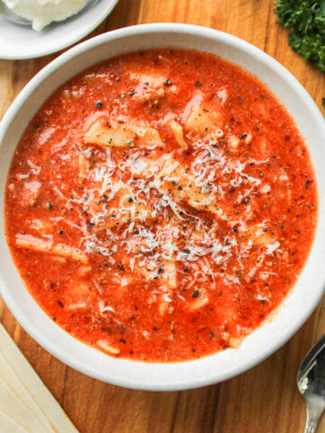 close up of one pot lasagna soup in a white ceramic bowl on a wooden board