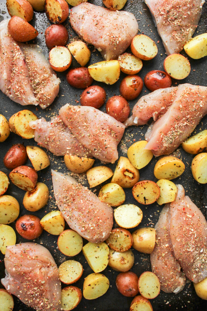 uncooked chicken and potatoes on a sheet pan