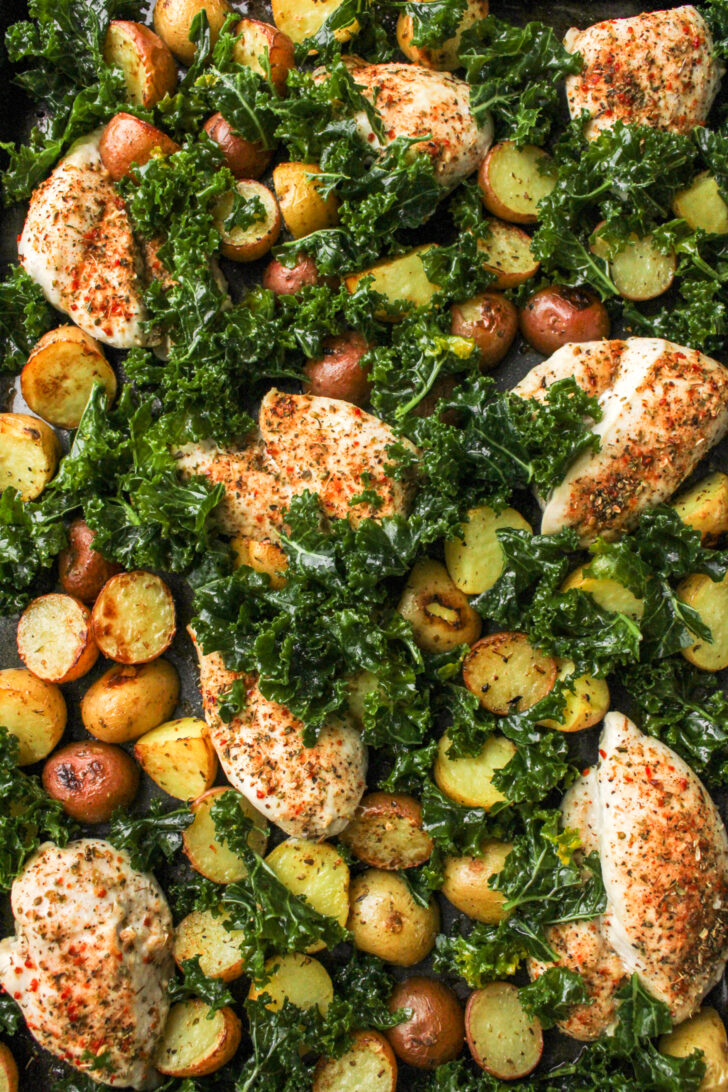 cooked chicken thighs, potatoes and kale on a sheet pan