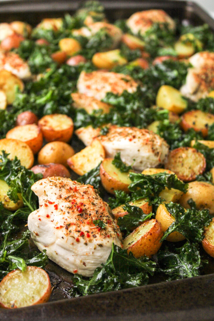 Mediterranean chicken thighs and potatoes with kale on a sheet pan