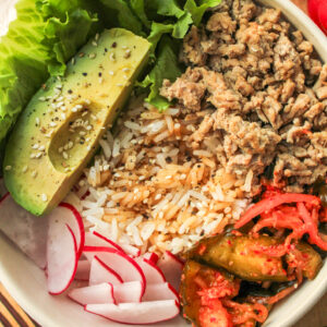 high protein kimchi rice bowls in a white ceramic bowl on top of a wooden cutting board
