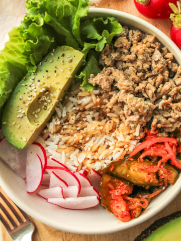 high protein kimchi rice bowls in a white ceramic bowl on top of a wooden cutting board